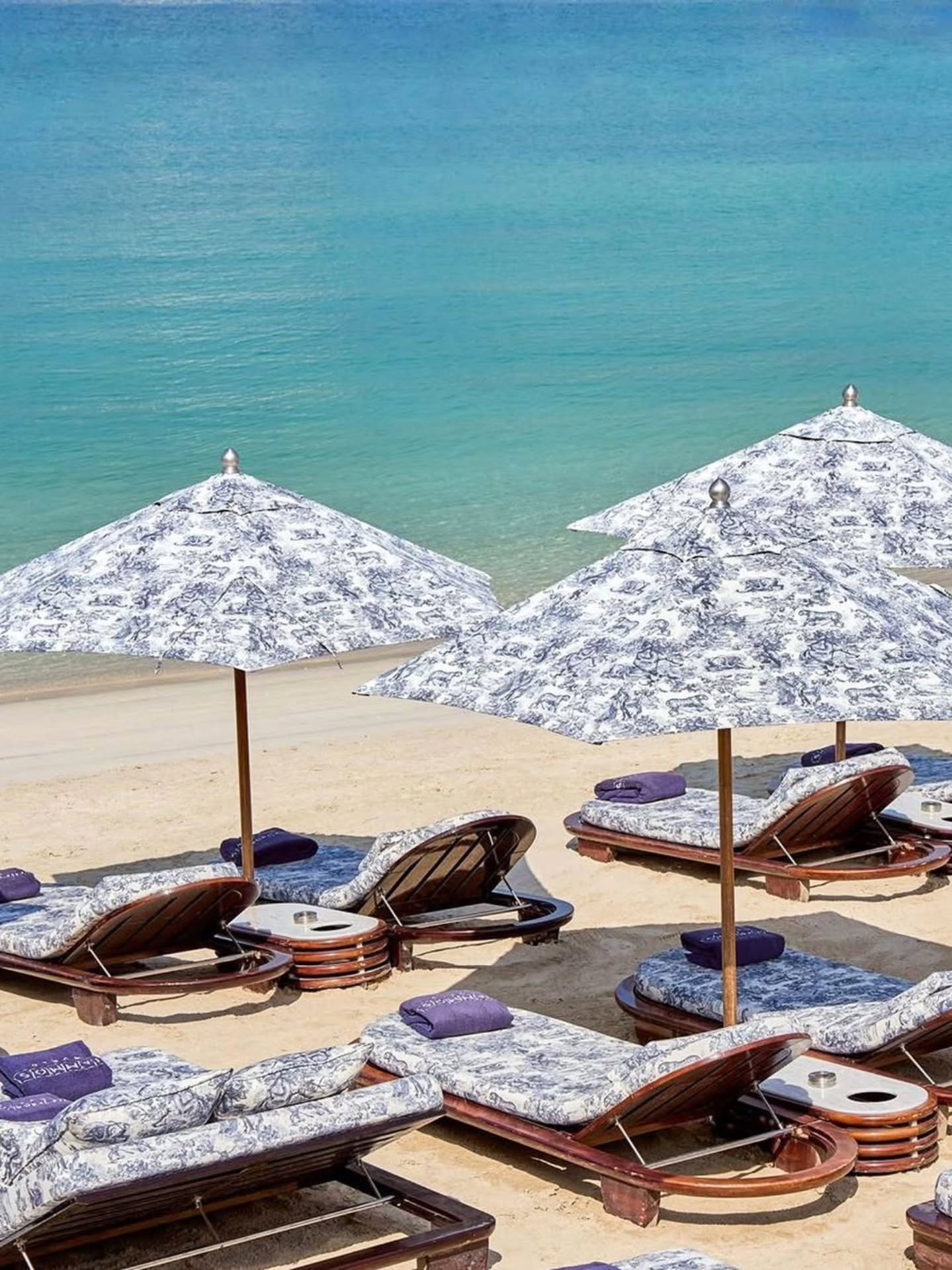 Reserved beach club loungers beside clear turquoise water