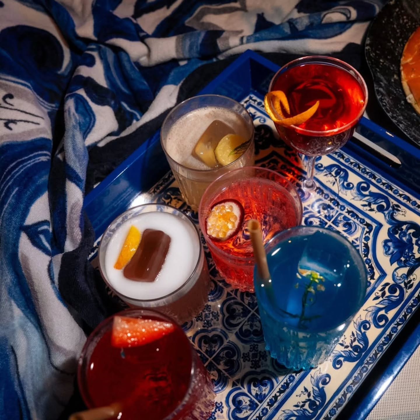 Colorful signature cocktails served on a blue patterned tray